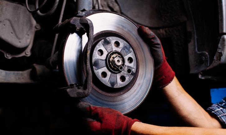 A brake disc and caliper being inspected by a technician.