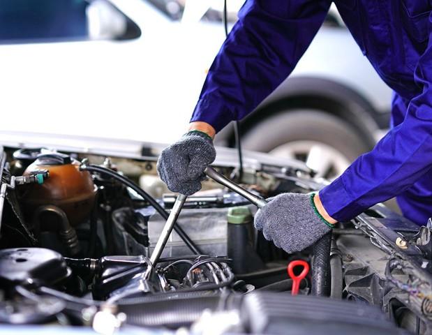 A technician working under the bonnet of a vehicle.